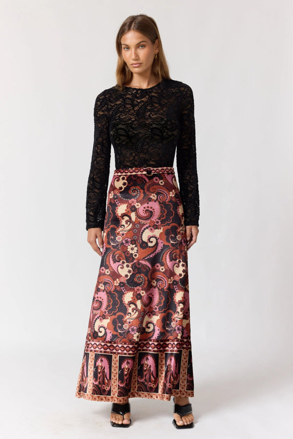 Woman wearing a black lace top and patterned skirt on a white background